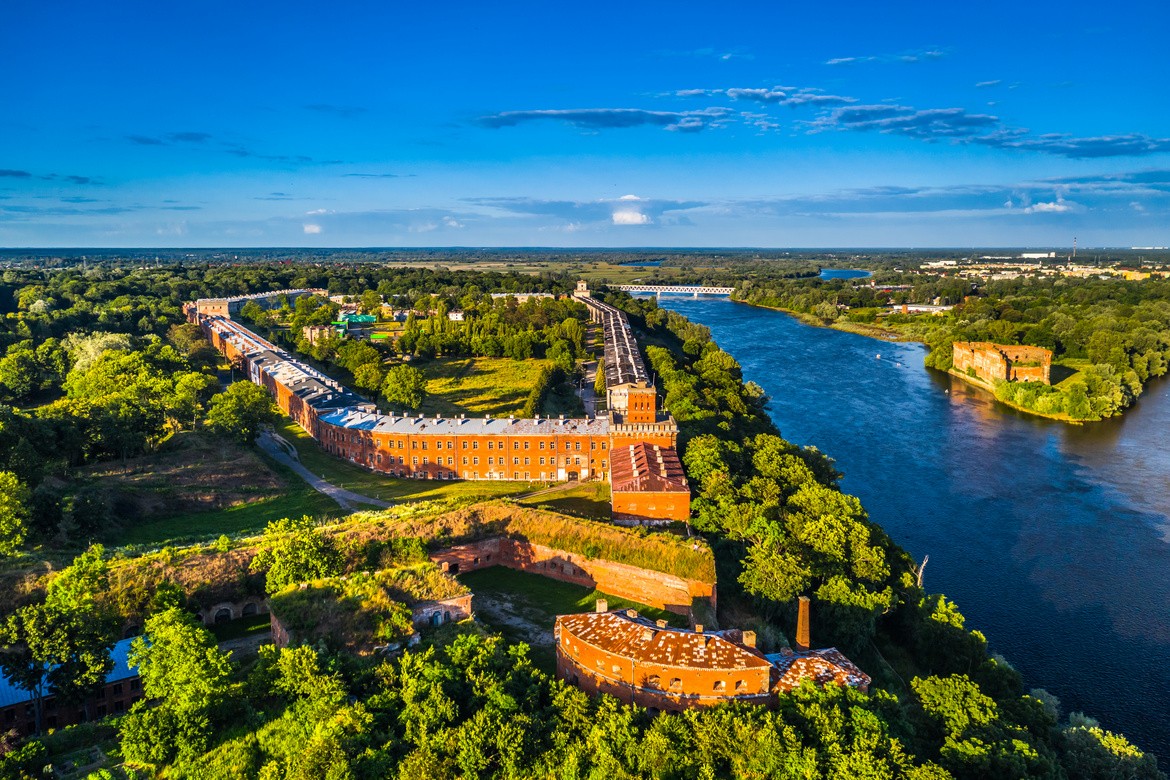 Widok z lotu ptaka na zabudowania Twierdzy Modlin nad rzeką.