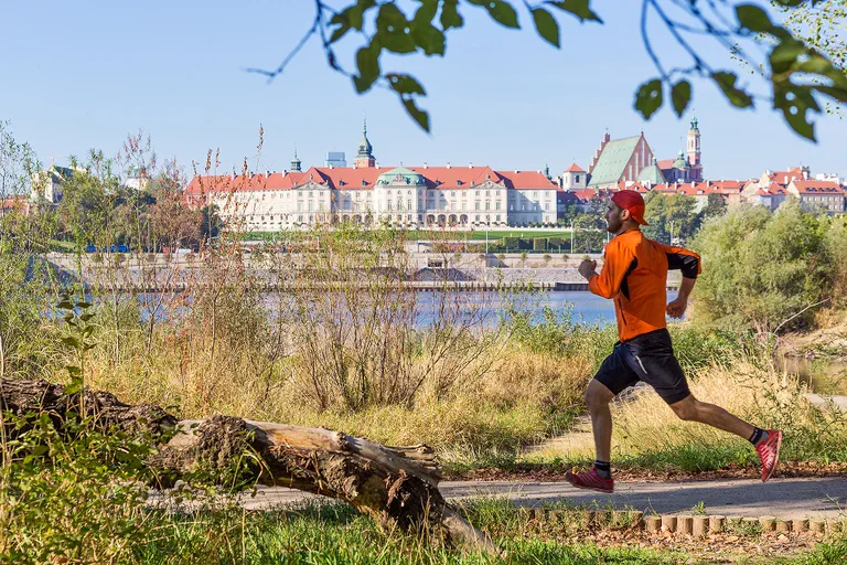 A runner on a recreational path by the Vistula, with Warsaw in the background.
